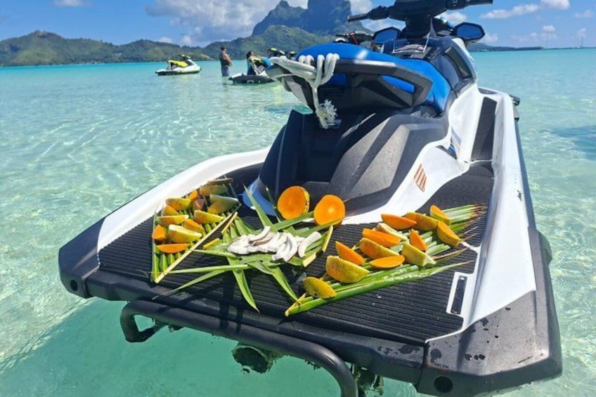 A jet ski on clear turquoise water with a grill loaded with food items. 2