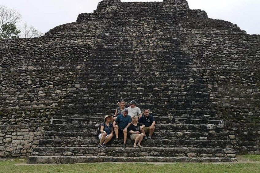 A group of people sitting on stone steps in front of a large ancient pyramid. 3