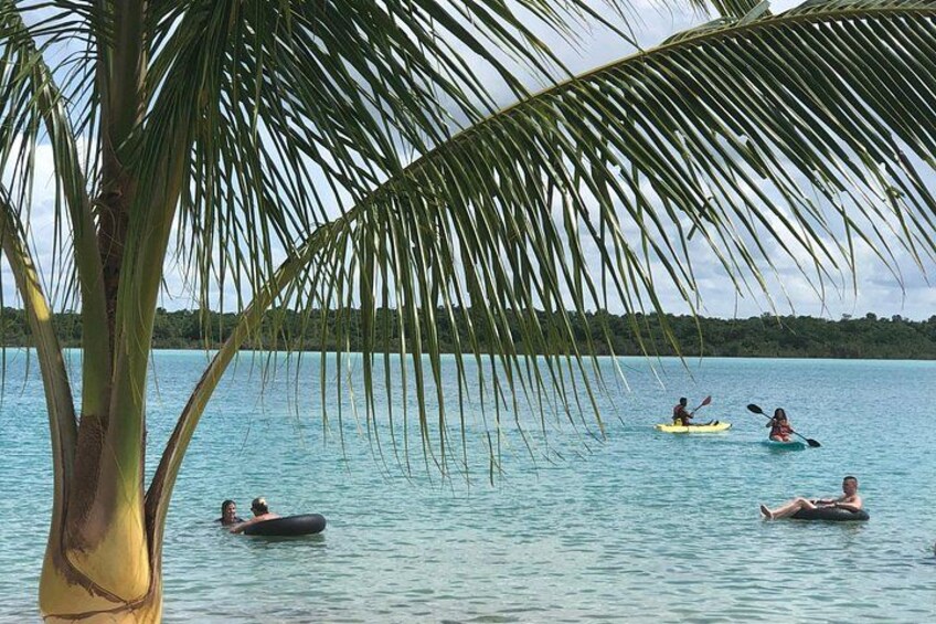 A calm sea with people kayaking and floating on a raft. 2