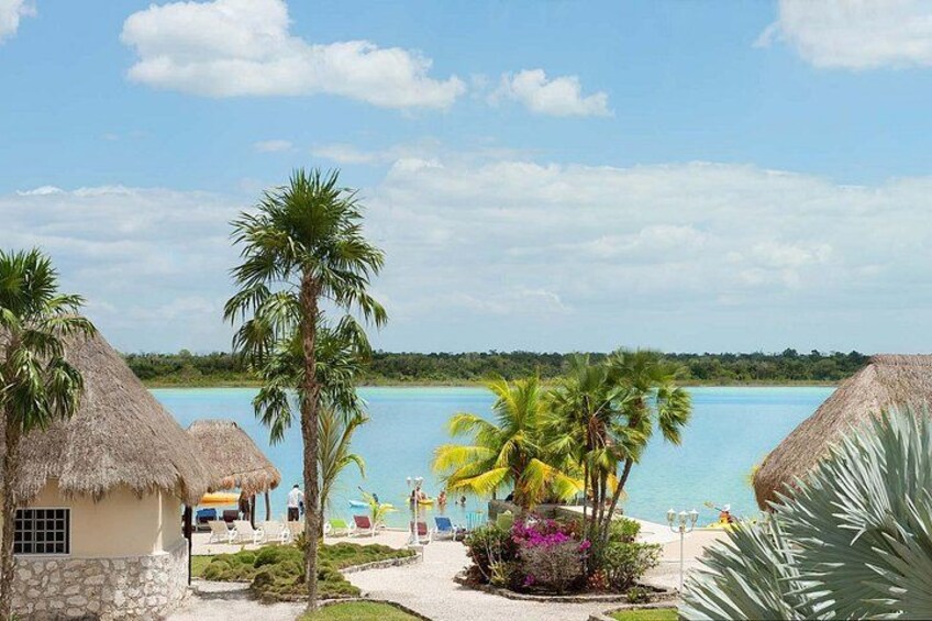 Un resort tropical con cabañas de techo de paja, palmeras y un mar azul cristalino. 3