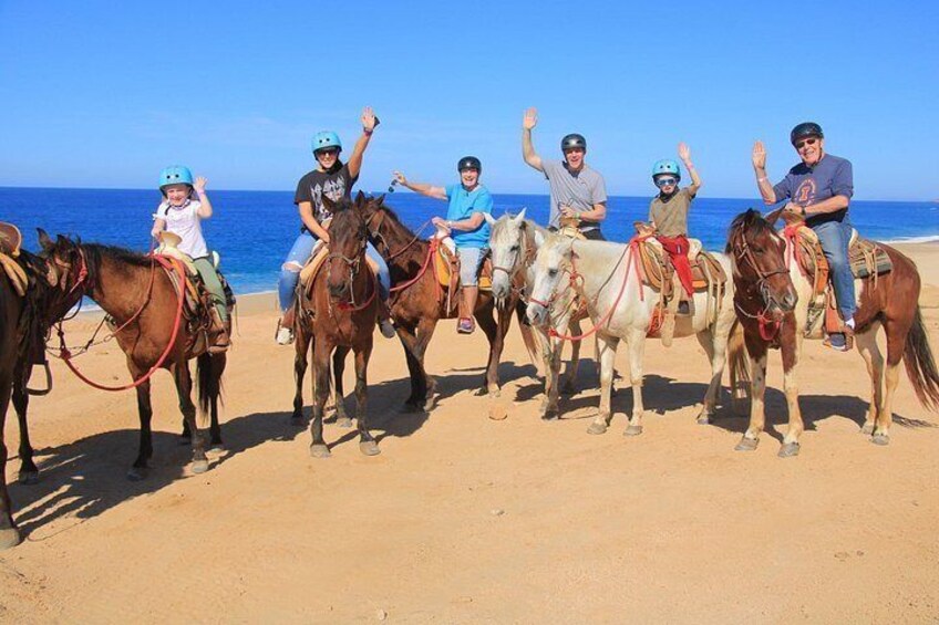 En gruppe mennesker rider på heste på en strand med havet i baggrunden. 3