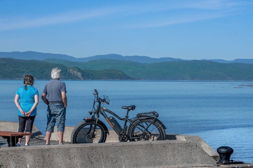 Deux personnes se tiennent près d’un lac, à côté d’un vélo. 3