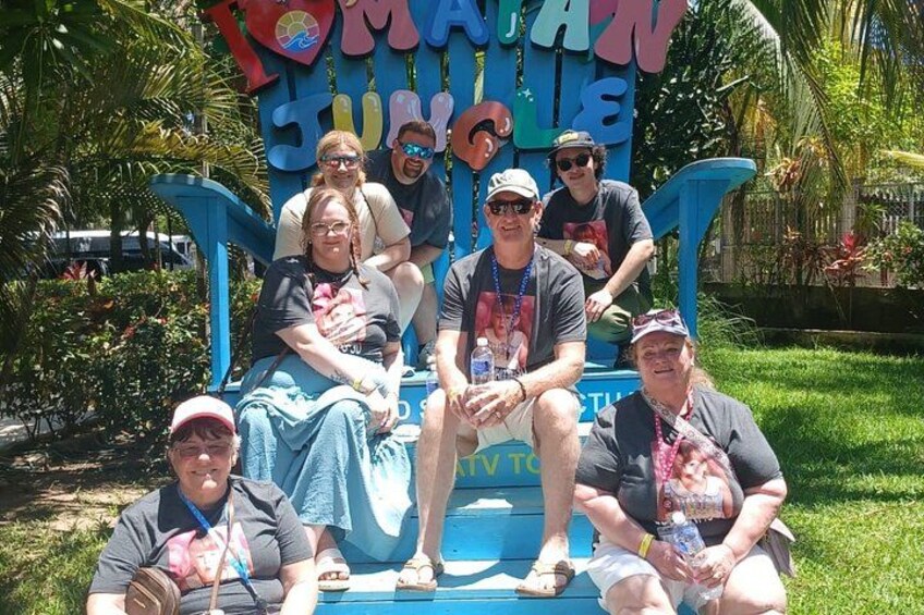 A group of people sitting on a blue bench with a sign that reads 'Tommy's Tummy.' 2