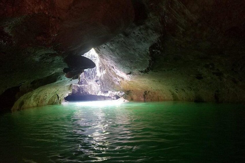 A cave with a pool of water and a natural opening. 1