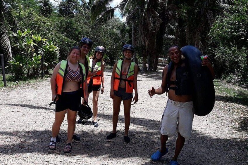 Un grupo de personas con chalecos salvavidas y cascos caminando por un sendero de tierra rodeado de vegetación. 3