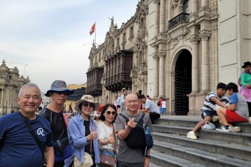 A group of people posing in front of a historic building with ornate architecture. 2