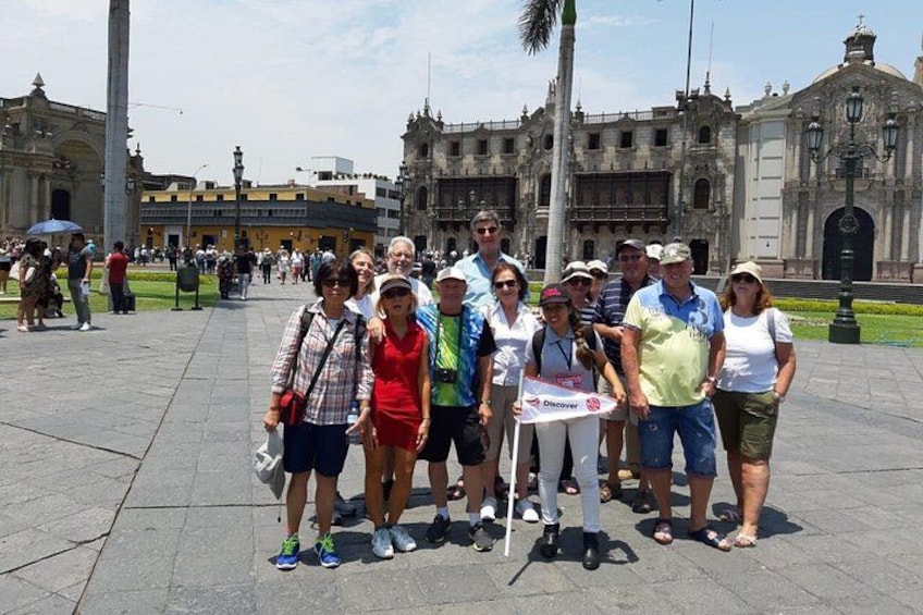 A group of people posing in a plaza with historical buildings in the background. 2