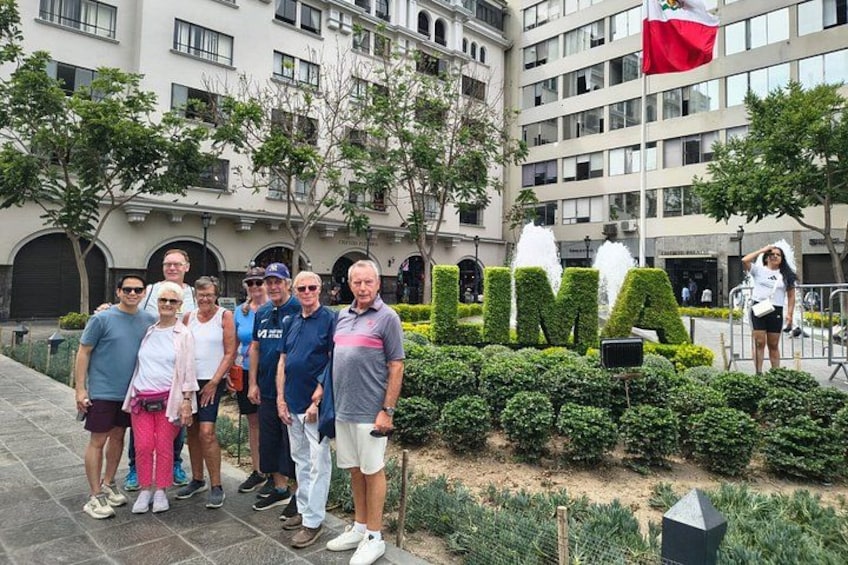 A group of people standing in front of a building with a sign that reads 'LIMA'. 1
