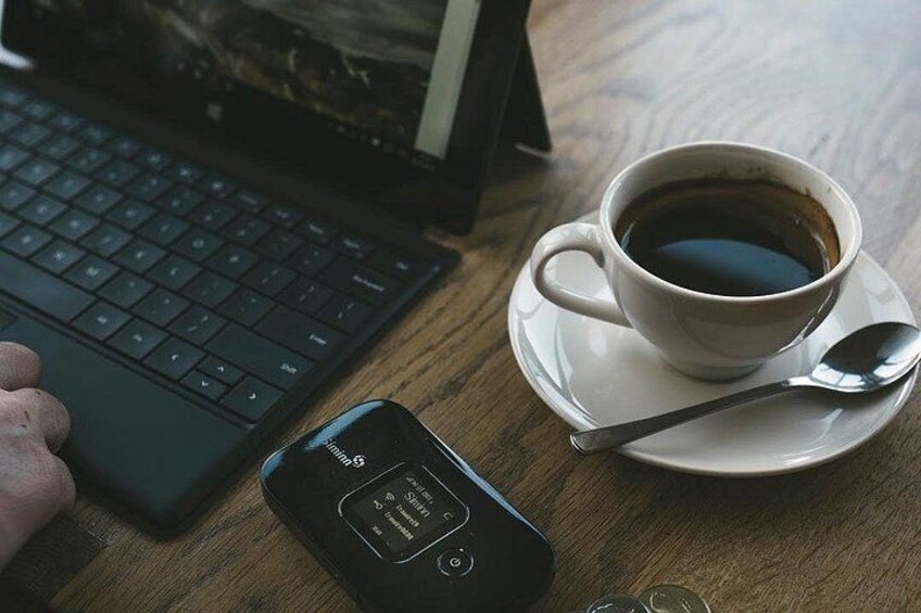 Una computadora portátil, una taza de café, una cuchara y un llavero de coche sobre una mesa de madera. 3