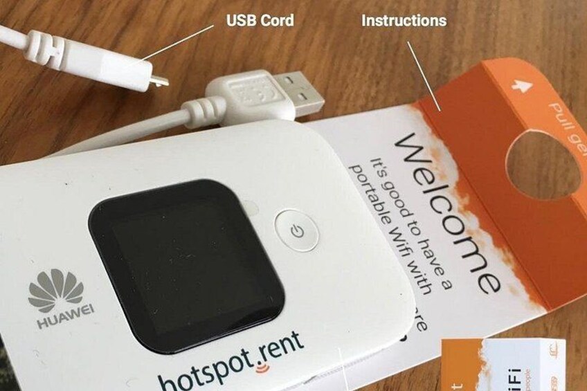 Un dispositivo Huawei tipo punto de acceso, un cable USB e instrucciones sobre una superficie de madera. 4