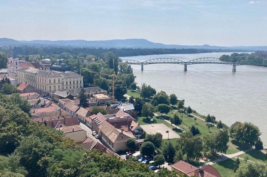 A riverside town with a prominent bridge, historic buildings, and lush greenery. 1