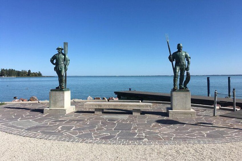 Deux statues sur une promenade en bord de mer, avec un ciel dégagé. 2