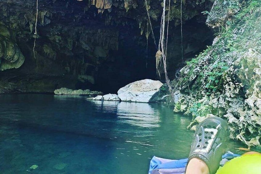 Una cueva con agua cristalina, una roca grande y una cuerda colgando del techo. 3