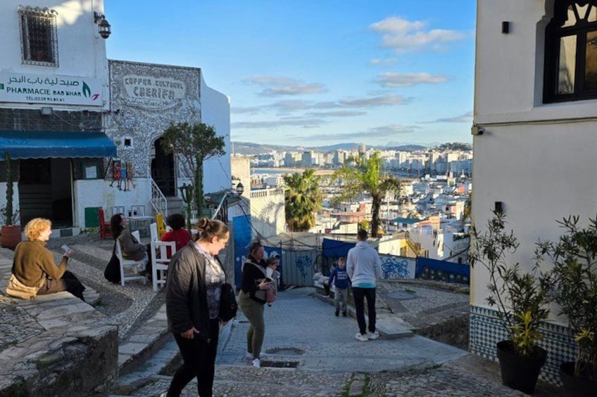 A cobblestone street with people walking, a pharmacy, and a view of a cityscape. 2