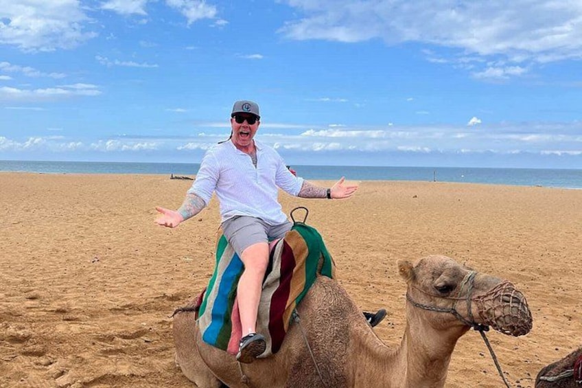 A person riding a camel on a sandy beach with the ocean in the background. 3
