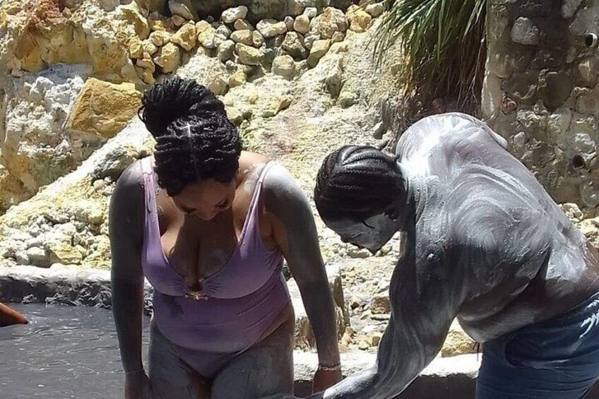 A person in a purple swimsuit and another in a gray swimsuit near a rocky shore. 5