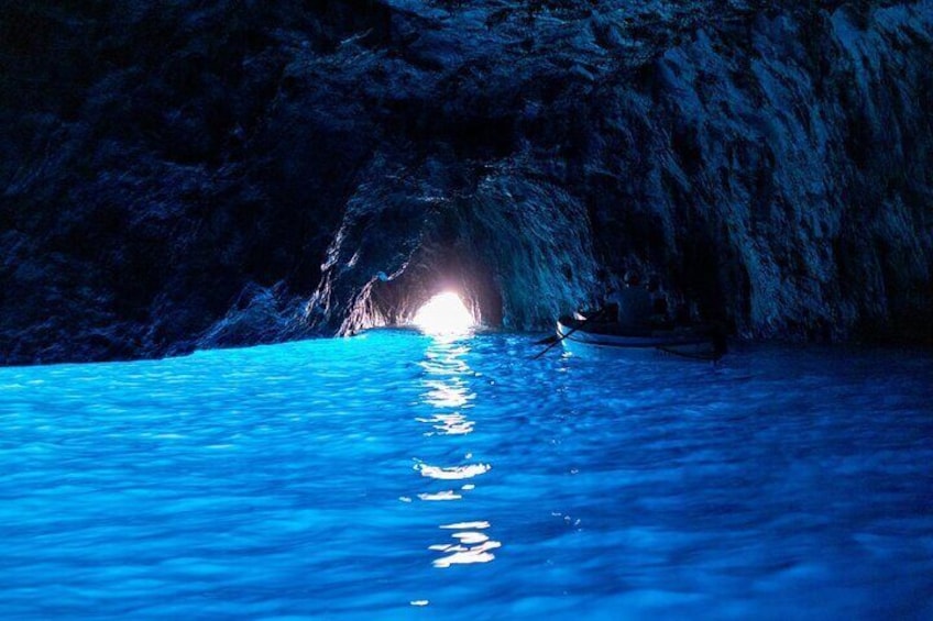 A boat in a cave with a blue light at the entrance. 1