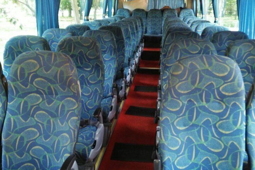 Het interieur van een bus met blauw gestreepte stoelen en een rood tapijt. 1