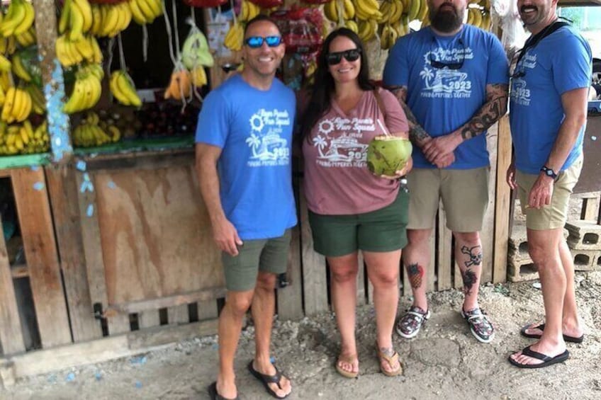 Cuatro personas frente a un puesto de frutas con plátanos. 1