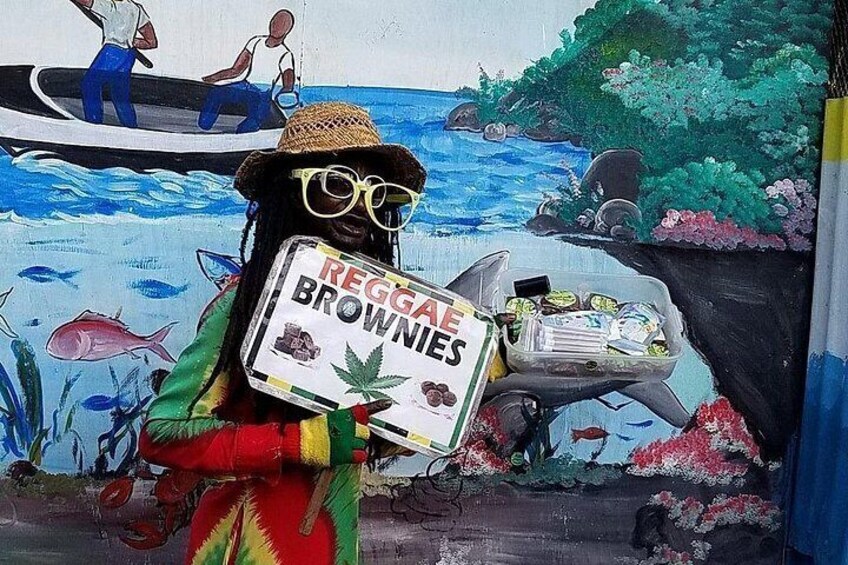 Un mural con un personaje sosteniendo un letrero que dice 'Regga Brownies', un barco con gente y una escena costera con peces y flores. 2
