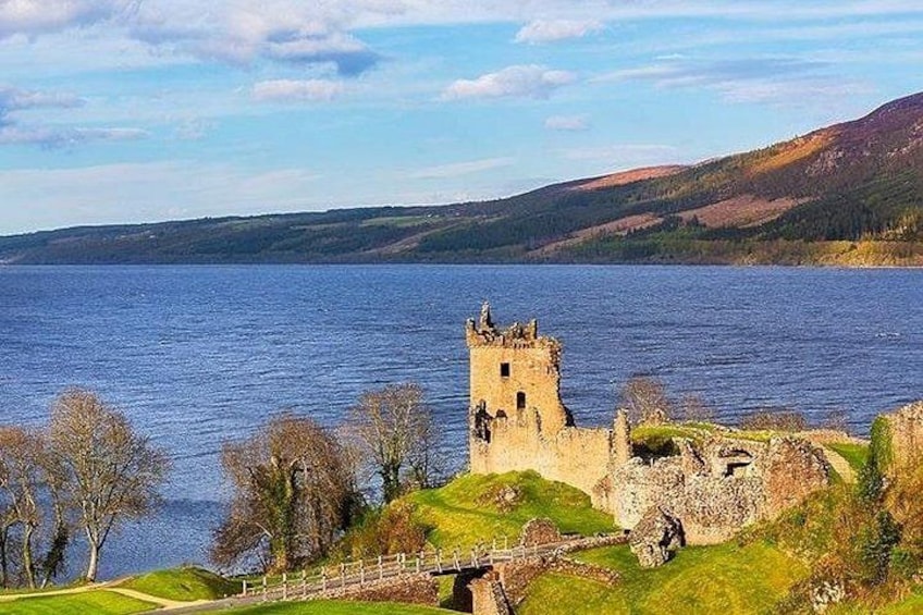 A historic tower and ruins by a lake with a clear sky. 1