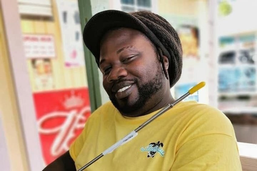 A person in a yellow shirt holding a cane, standing in front of a storefront with a Coca-Cola logo. 4