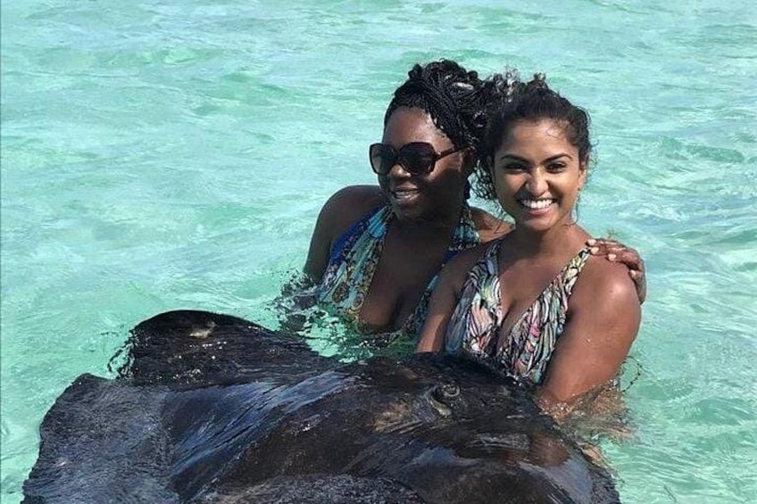 Two people in clear water, one holding a large black object. 5