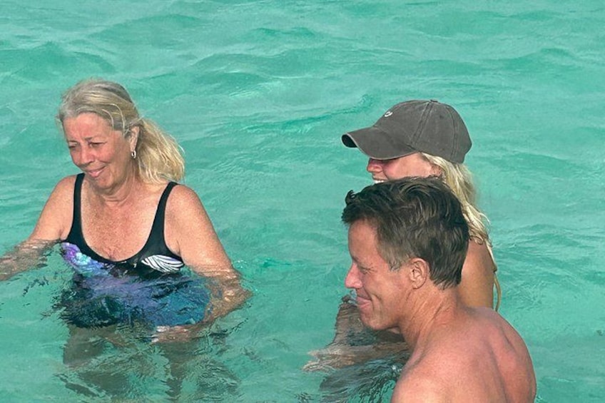 A person in a black swimsuit and another in a gray cap swimming in clear water. 5
