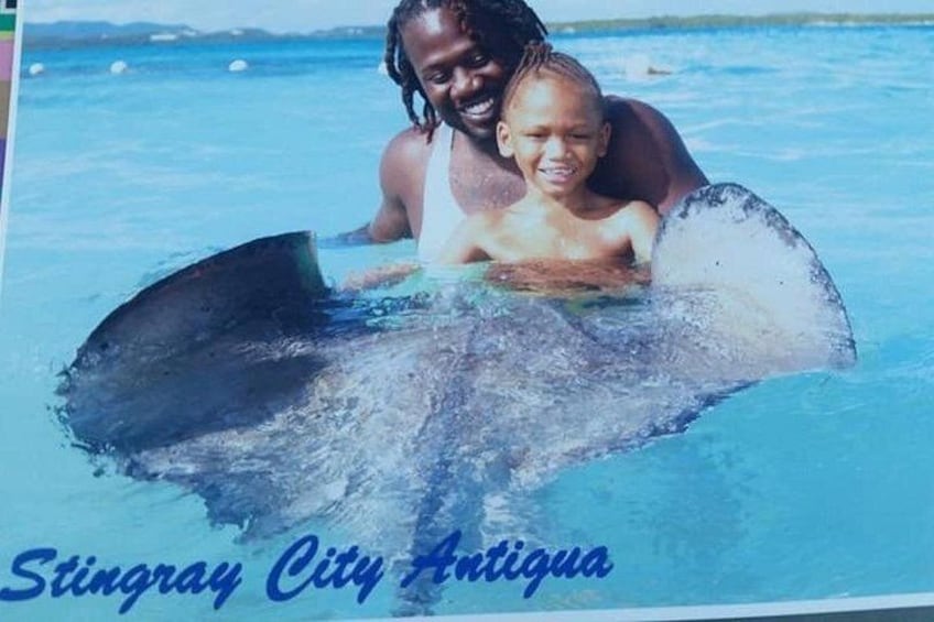 A stingray in the water with a person and a child. 3