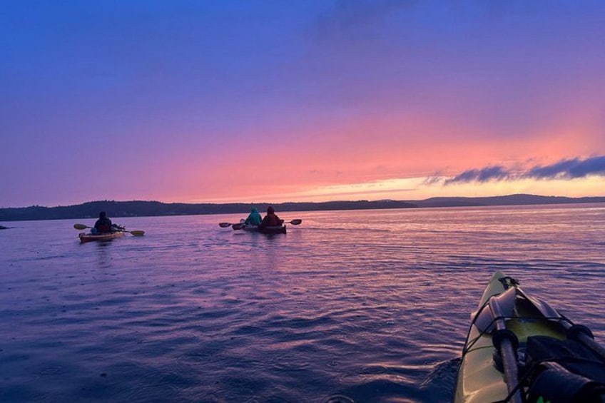 Des personnes pratiquant le kayak sur une étendue d'eau calme au coucher du soleil. 2