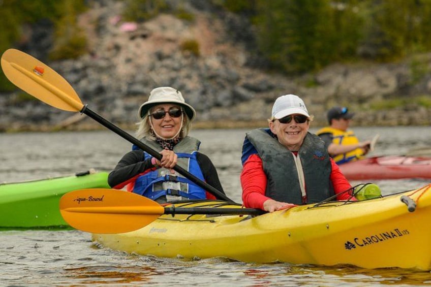 Deux personnes pratiquent le kayak sur une étendue d’eau calme, portant des gilets de sauvetage et maniant des pagaies. 3