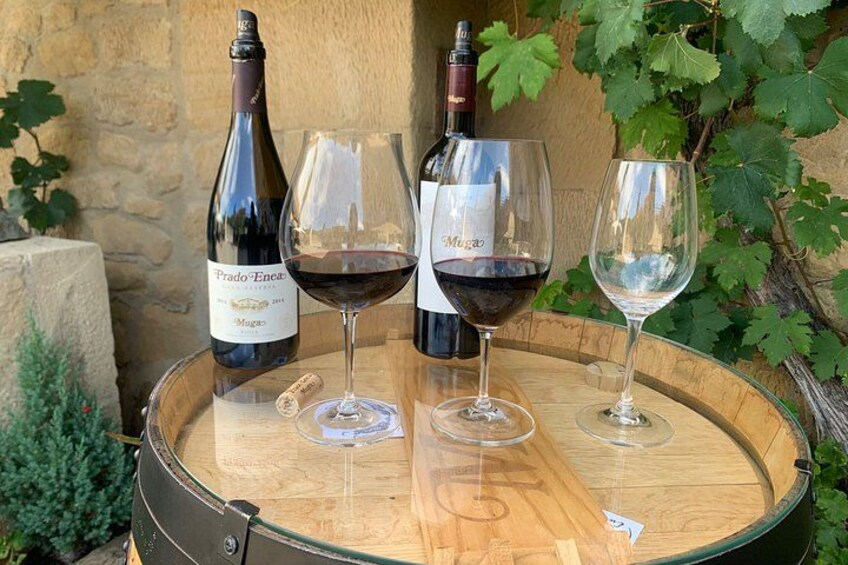 Two wine bottles and three wine glasses on a wooden barrel. 5