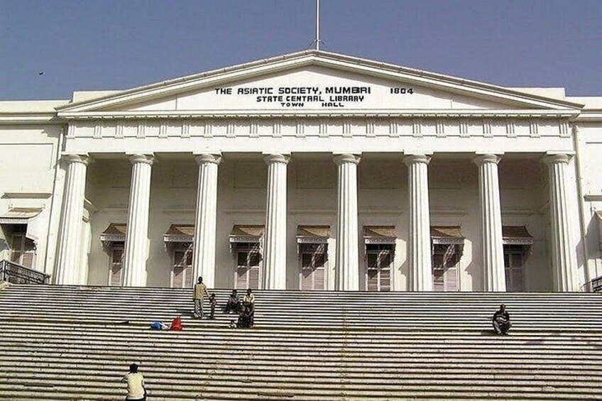 A large white building with columns and a sign that reads 'The Asiatic Society, Mumbai, 1904 State Central Library Hall.' 5