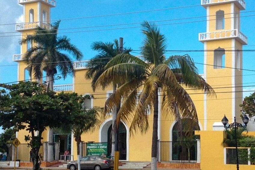 A yellow building with a tower, palm trees, and a street. 3