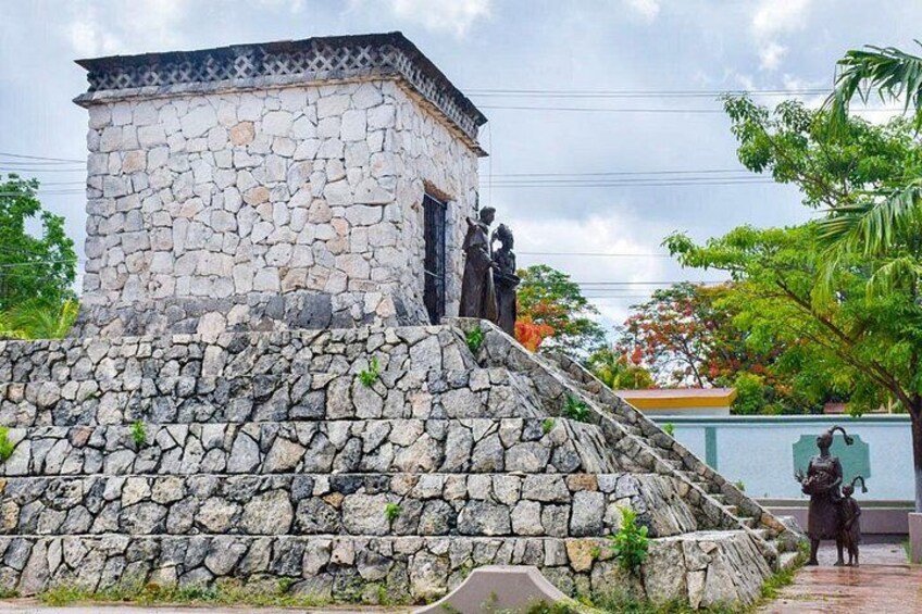 A stone monument with statues, a staircase, and a statue of a dog. 4