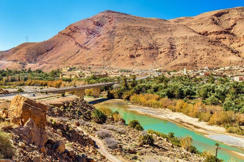 A desert landscape with a river, a bridge, and a mountain in the background. 5