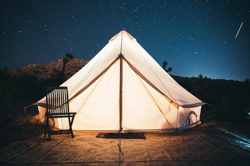 A tent with a chair in front, set on a wooden deck under a starry night sky. 3