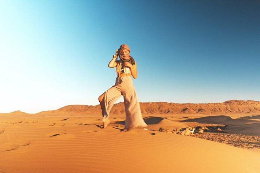A person in a desert landscape with sand dunes and a clear sky. 3