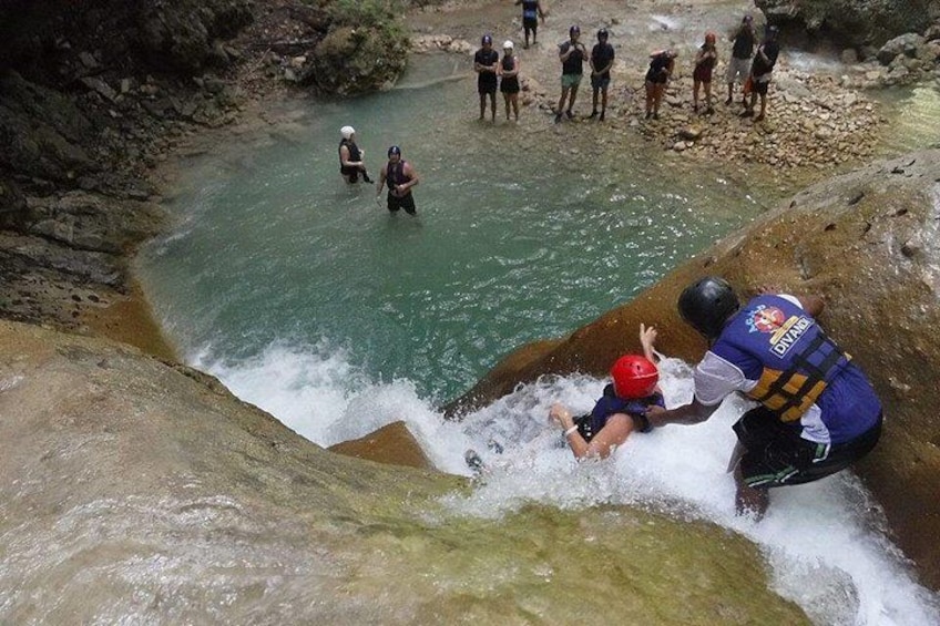 A person sliding down a water slide with a lifeguard assisting. 1