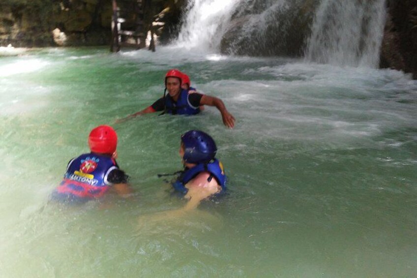 Personas en el agua con cascos, una cascada al fondo. 1