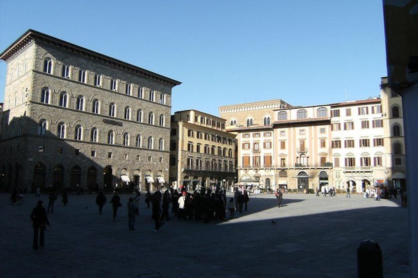 Una piazza storica con architettura classica, un ampio spazio aperto e persone che passeggiano. 1