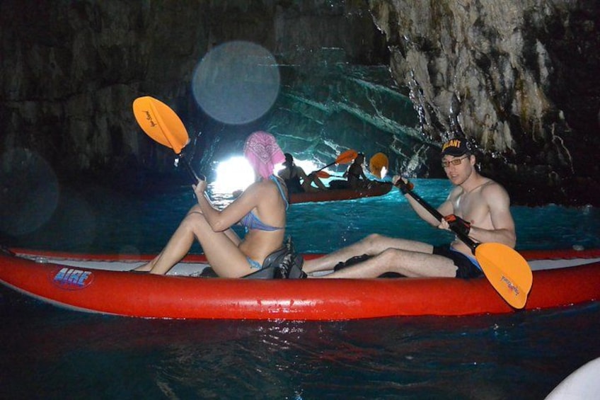 Twee personen in een rode kajak op het water, met een rotsachtige achtergrond. 1