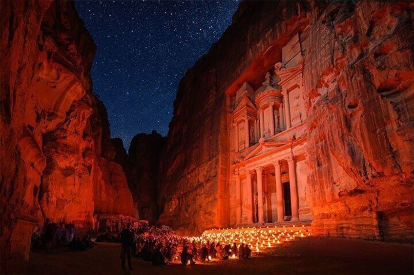 A night scene at Petra with a starry sky, illuminated rock formations, and a temple structure. 2