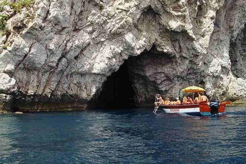 A boat with passengers near a rocky cave entrance. 1