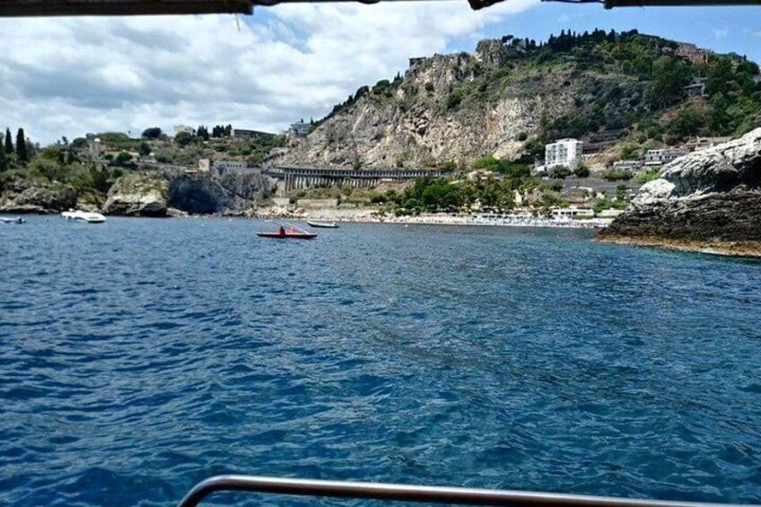 A coastal landscape with a rocky hill, a bridge, and boats on the water. 3