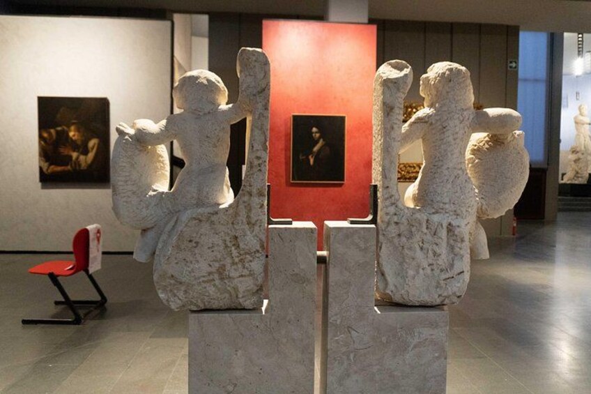 A sculpture installation in an art gallery with a red panel in the background. 5