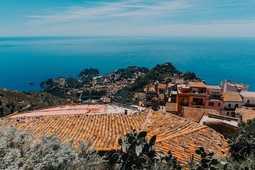 Una località costiera con tetti in terracotta, un mare cristallino e un paesaggio collinare sullo sfondo. 2