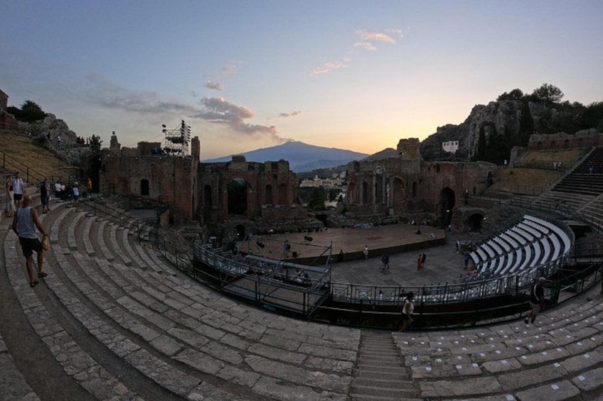 Un antico anfiteatro con gradinate in pietra e rovine, immerso in un paesaggio montuoso. 3