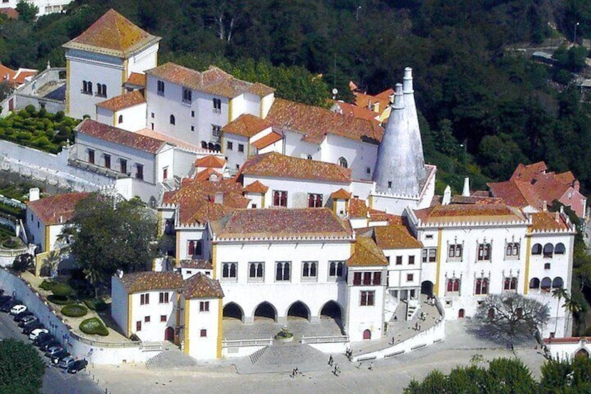 A historic town with white buildings, red-tiled roofs, and a prominent bell tower. 2