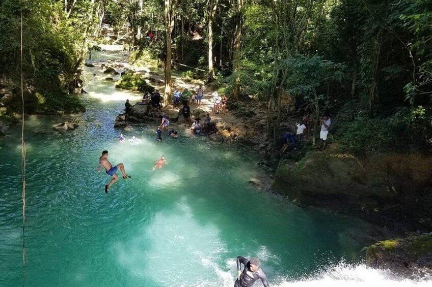 A river with people swimming and a person jumping into the water. 2